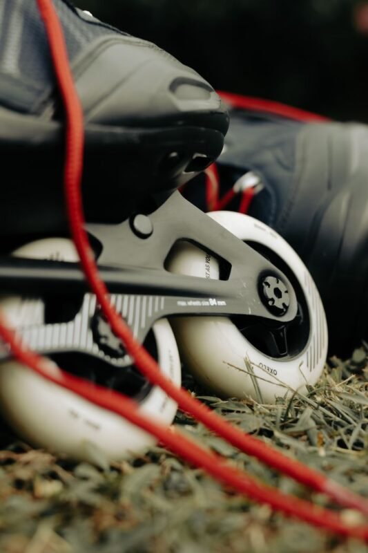 Home Detailed view of rollerblades with vibrant red laces, resting on grass, perfect for active lifestyle themes.